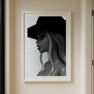 May include: Monochrome framed print of a doll with a black hat and cigarette. The doll has long, wavy blonde hair. The print is displayed in a hallway with a black window frame and a wooden floor. The image is in a white frame.