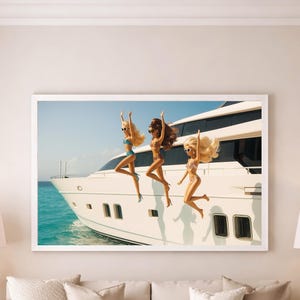 May include: A framed print featuring three dolls jumping off a white yacht into turquoise water under a clear blue sky. The dolls have different skin tones and wear swimwear. The yacht is the focal point of the image.