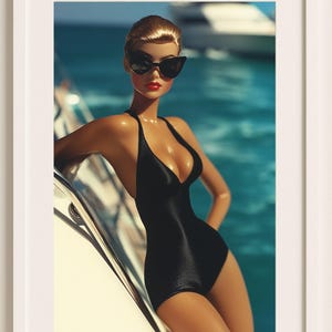 May include: A framed print featuring a doll in a black swimsuit and sunglasses, posing on a yacht. The doll has red lipstick and blonde hair. The background shows blue water and a boat.