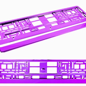 May include: A pair of shiny, purple license plate frames. The frames are rectangular with a series of cut-out shapes and a separate, matching purple bar. The frames are designed to hold a standard license plate.