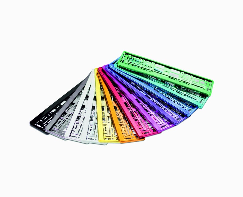 May include: A collection of colorful license plate frames in various metallic finishes, including black, silver, gold, and vibrant shades of green, blue, and purple. The frames are arranged in a fan shape against a white background.