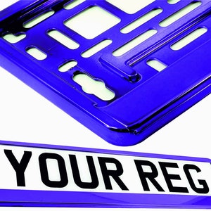 May include: A shiny blue license plate frame and a matching license plate. The license plate has the text "YOUR REG" in bold black letters on a white background. The frame has a glossy finish.