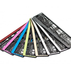 Puede incluir: Un conjunto de diez marcos para placas de matrícula en varios colores, incluyendo rojo, rosa, azul, verde, amarillo, beige, blanco, plateado y negro. Los marcos están hechos de plástico y tienen una superficie texturizada.