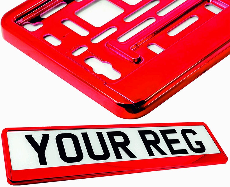 May include: A red license plate frame and plate. The frame is a shiny, metallic red with cut-out sections. The plate is white with black text that reads "YOUR REG" in a bold font. The items are against a white background.