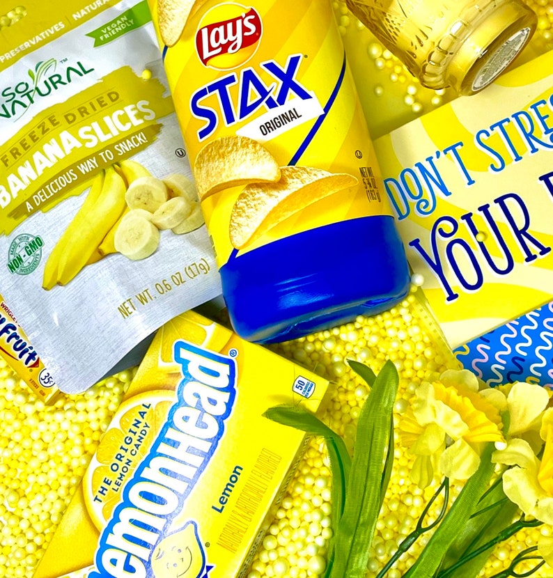 May include: A yellow and blue bag of Lay's Stax Original potato chips, a yellow bag of freeze-dried banana slices, a yellow box of Lemonhead candy, and a yellow sign that says "Don't stress your yes" with yellow and blue polka dots in the background.