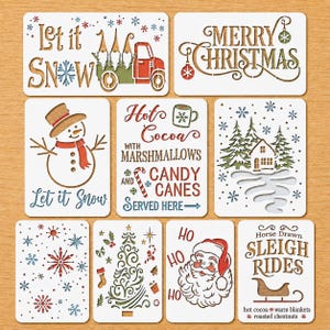 May include: A set of ten rectangular white stencils featuring various holiday designs including a truck with gnomes, a snowman, a Christmas tree, Santa Claus, a sleigh, snowflakes, and text such as Let it Snow, Merry Christmas, and Hot Cocoa.