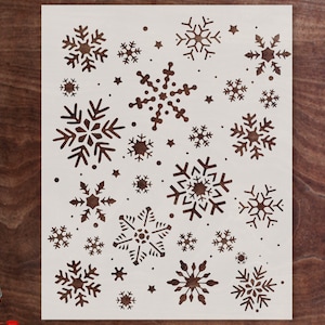May include: White stencil with a design of multiple snowflakes in various sizes and shapes. The stencil is perfect for creating winter-themed crafts and decorations.