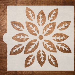 May include: White stencil with a floral design featuring a circle in the center and 12 leaves radiating outward.