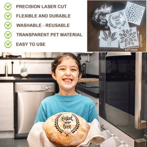 May include: A child holds a loaf of bread with the words "Baked with love" stamped on it. The bread is surrounded by a wreath of leaves. The child is smiling and standing in a kitchen. The image also shows a set of four reusable baking stencils with various designs, including a wreath, wheat stalks, a flower, and stars.
