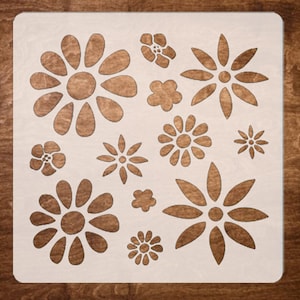 May include: A white stencil with a design of multiple flowers. The flowers are in various sizes and shapes, with some having a more intricate design than others.