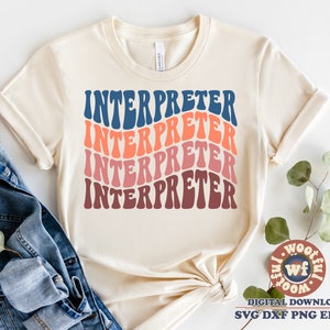 May include: A beige t-shirt with the word "INTERPRETER" repeated four times in a rainbow pattern of blue, orange, pink, and maroon. The word is in a retro, wavy font.