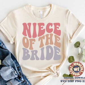 May include: A white t-shirt with the text "Niece of the Bride" in a retro font with pink, orange, and purple colors.