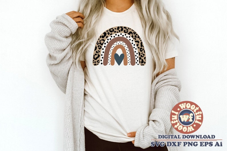 Peut inclure: Un t-shirt blanc avec un motif arc-en-ciel brun, bleu et blanc avec un c&oelig;ur au centre. L'arc-en-ciel est bord&eacute; d'un motif l&eacute;opard.