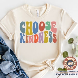Può includere: Una maglietta beige con il testo "Choose Kindness" in lettere retrò colorate. Le lettere sono in tonalità di giallo, arancione, rosso, verde, blu e viola.