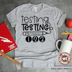Puede incluir: Una camiseta gris con texto negro que dice "testing TESTING 123". El texto está estilizado para parecer un lápiz con una goma de borrar.