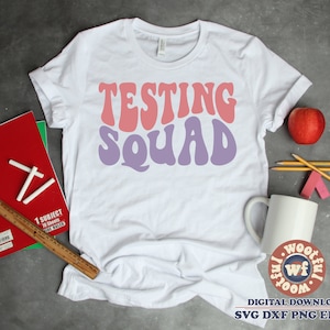 May include: White t-shirt with the text "TESTING SQUAD" in pink and purple retro font.
