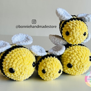 May include: Three handmade plush bees in different sizes. The bees are yellow with black stripes and black eyes. They have white and pale blue wings. The text "bonniehandmadestore" is visible in the image.
