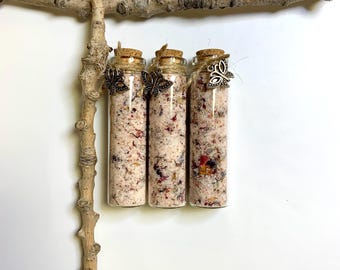 May include: Three small glass bottles filled with bath salts and dried flowers. Each bottle has a cork stopper and a silver butterfly charm.