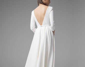 May include: A white midi dress featuring three-quarter length sleeves, a deep V-shaped open back, and a pleated skirt. The garment includes a thin waistband and is paired with white high-heeled shoes that have a distinct red sole detail.