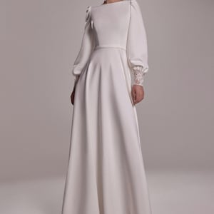Abito da sposa Camila in crêpe, modello a trapezio, sobrio ed elegante: scollo a barca e maniche a sbuffo.