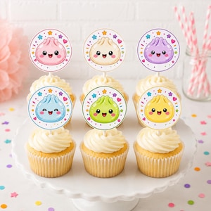 Peut inclure: Six cupcakes disposés sur un présentoir blanc, chacun surmonté d'une décoration en papier circulaire représentant un personnage de boulette de style kawaii souriant. Les boulettes sont roses, crème, violettes, bleu clair, vert citron et jaunes, entourées de petites étoiles et cœurs colorés.