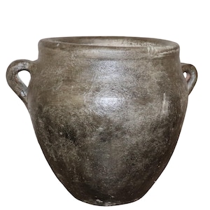 Peut inclure: Un pot en céramique grise texturée avec deux anses en boucle. Le pot a une large ouverture et un corps arrondi, avec une surface légèrement rugueuse. La couleur est un gris sourd avec des ombres plus foncées, suggérant un aspect vieilli. Le pot est probablement à usage décoratif ou fonctionnel.