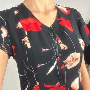 Peut inclure: Une robe noire &agrave; manches courtes avec un imprim&eacute; floral rouge et blanc. La robe a un col en V et un devant boutonn&eacute;.