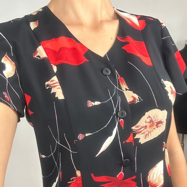 Peut inclure: Une robe noire &agrave; manches courtes avec un imprim&eacute; floral rouge et blanc. La robe a un col en V et un devant boutonn&eacute;.