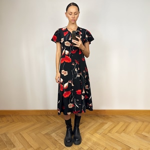Peut inclure: Une femme portant une robe midi noire &agrave; imprim&eacute; floral rouge et des bottines noires &agrave; la cheville.
