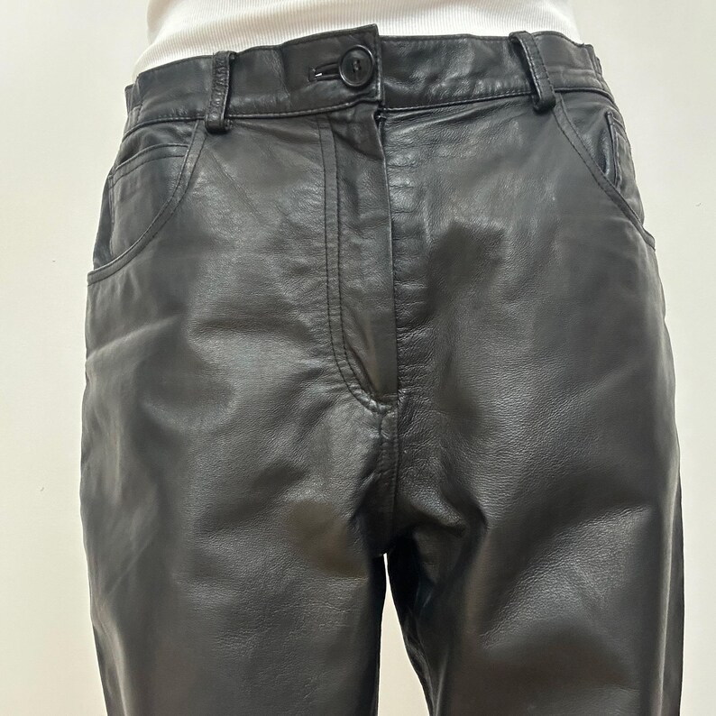 Peut inclure: Pantalon en cuir noir avec braguette boutonn&eacute;e et deux poches avant.