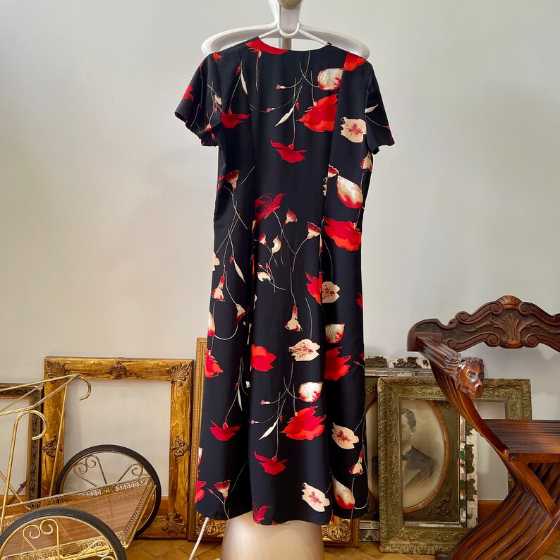 Peut inclure: Une robe maxi noire &agrave; imprim&eacute; floral avec des fleurs de pavot rouges et blanches. La robe a un col en V et des manches courtes.