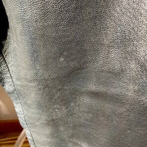 Peut inclure: Gros plan sur une veste en cuir noire avec une surface lisse et textur&eacute;e.