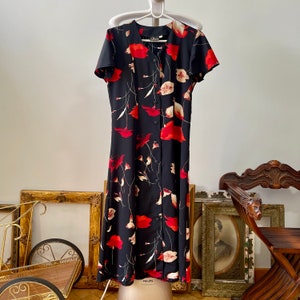Peut inclure: Une robe midi noire &agrave; imprim&eacute; floral de coquelicots rouges et un devant boutonn&eacute;. La robe a des manches courtes et une coupe ample.