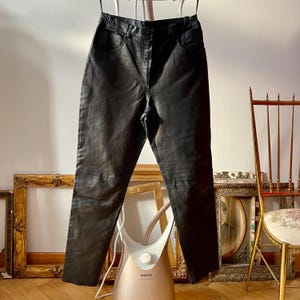 Peut inclure: Pantalon en cuir noir suspendu &agrave; un cintre. Le pantalon est ajust&eacute; et taille haute. Il est en bon &eacute;tat et a un look vintage.