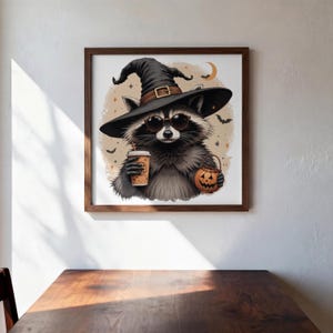May include: A framed square wall art print featuring a gray raccoon wearing a black witch hat with a brown band and dark sunglasses. The raccoon holds a tan coffee cup and a small orange jack-o'-lantern bucket against a beige background.