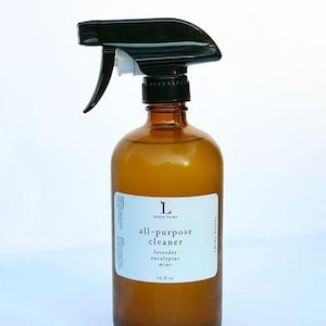 May include: A brown glass bottle with a black spray nozzle. The bottle is labelled "all-purpose cleaner" with the text "lavender eucalyptus mint" and "16 fl oz".