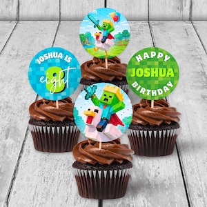 Può includere: Cinque cupcake al cioccolato con glassa marrone e decorazioni. Le decorazioni presentano personaggi pixelati e le frasi "Joshua is eight" e "Happy Joshua Birthday". I cupcake sono disposti su una superficie di legno chiaro.