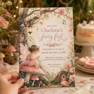May include: A rectangular birthday party invitation featuring a fairy sitting on a mushroom, surrounded by pink flowers, butterflies, and a hanging lantern. The text reads: Join us for Charlotte's fairy first birthday party, Saturday, May 16th at 2:30 PM, Willowbrook Garden House, 428 Rosewood Lane, Portland, OR, RSVP to Hannah at (503) 555-0186.