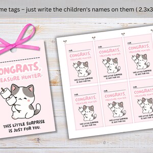May include: Pink name tags with a cartoon cat holding marshmallows. The tags read "Congrats, Treasure Hunter!" and "This little surprise is just for you." A pink ribbon is attached to one tag. Each tag is 2.3 x 3.5 inches.