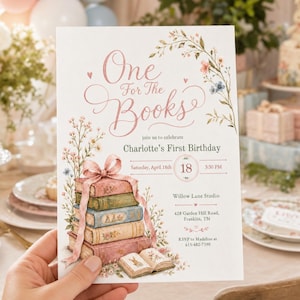 Puede incluir: Una tarjeta de invitación rectangular con una pila de cuatro libros ilustrados atados con una cinta rosa, decorada con enredaderas florales y el texto One For The Books, join us to celebrate Charlotte's First Birthday, Saturday, April 18th, 18, 3:30 PM.