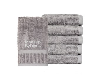 May include: A stack of six grey hand towels with the text "Makeup ByDiana" embroidered on the top towel.