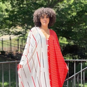 May include: A white and red patterned maxi dress with a V-neckline. The dress has a white side with vertical red and grey stripes and a red side with white polka dots.