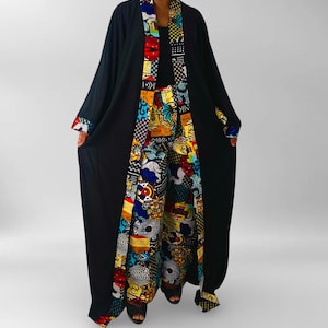 Könnte beinhalten: Schwarzes Roben- und Hosen-Set mit farbenfrohem Musterbesatz. Der Besatz zeigt eine lebendige Mischung aus roten, blauen, gelben und weißen geometrischen und abstrakten Designs. Die Robe hat lange Ärmel und eine fließende Silhouette.