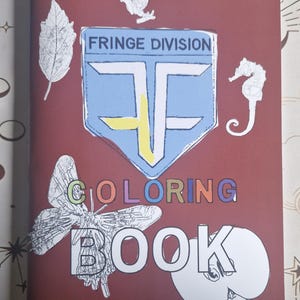 May include: A maroon coloring book with the words "COLORING BOOK" in colorful letters. The cover features a blue and yellow emblem with the text "FRINGE DIVISION". Decorative stickers of a butterfly, leaf, frog, seahorse, and apple are also on the cover.