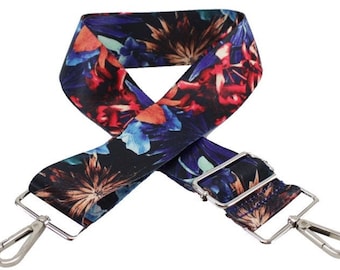 Pode incluir: Uma alça ajustável com fechos de metal prateado, com um padrão floral preto e azul. A alça é feita de tecido e é adequada para bolsas ou carteiras.