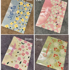 May include: Four plastic folders with floral patterns and personalised names. The folders are in blue, pink, cream, and green.