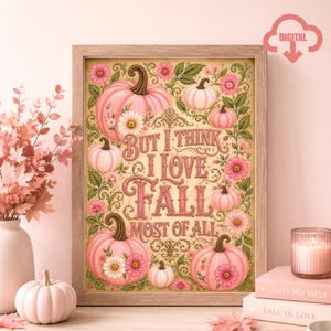 Może przedstawiać: Oprawiony wydruk artystyczny przedstawiający różowe dynie i kwiaty z napisem But I Think I Love Fall Most Of All. Wzór zawiera ozdobne zawijasy i liście w odcieniach różu, zieleni i kremu, umieszczony w jasnej drewnianej ramie.