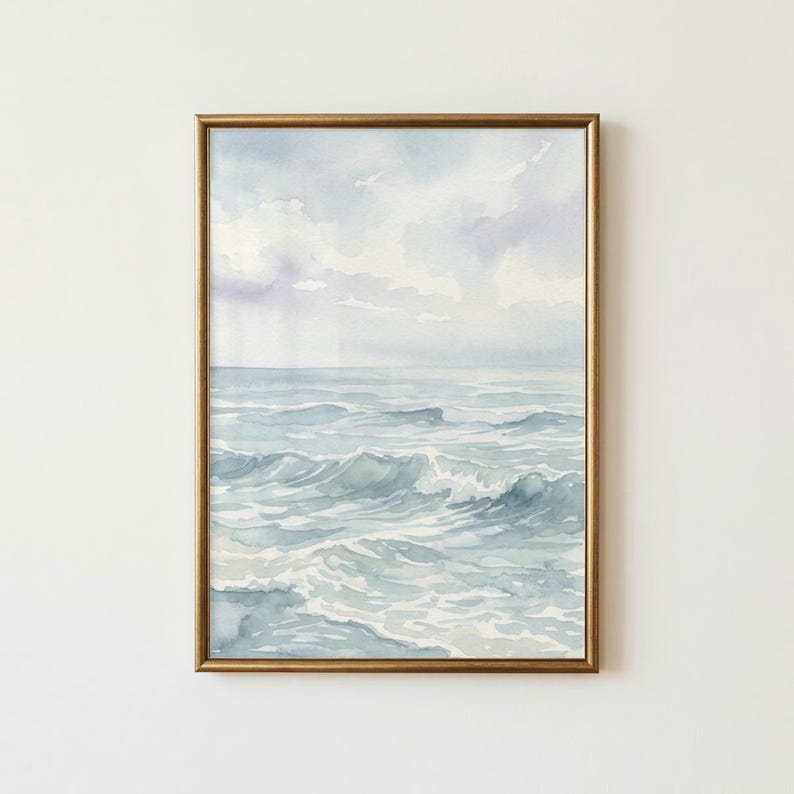 May include: A framed watercolor painting depicting a seascape with gentle ocean waves in shades of blue and grey under a soft, cloudy sky. The artwork is enclosed in a thin, metallic gold frame, showcasing fluid brushstrokes and light tones.