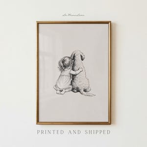 May include: A framed black and white print depicts a young child embracing a large, fluffy dog. The artwork is in a gold frame and features the text "La Mana Luna" at the top and "PRINTED AND SHIPPED" at the bottom.