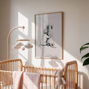 May include: A framed black and white print depicts a child embracing a large dog. The artwork is displayed above a wicker crib with a pink blanket and a mobile with cloud and ball ornaments. A stuffed bunny sits on the crib.